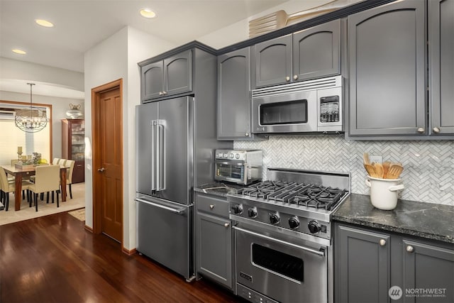 5613 21st Ave SW, Seattle, WA 98106 - kitchen featuring premium appliances, backsplash, dark wood finished floors, dark stone counters, and a chandelier