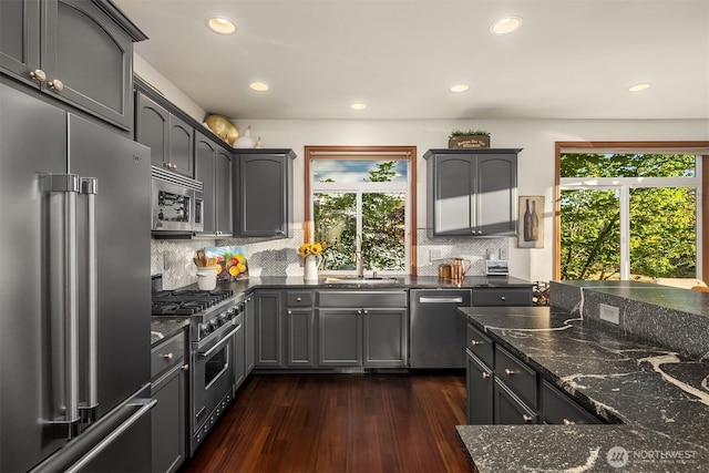 5613 21st Ave SW, Seattle, WA 98106 - kitchen with high end appliances, dark stone counters, dark wood-style flooring, recessed lighting, and decorative backsplash