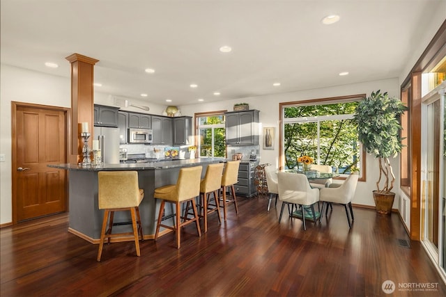 5613 21st Ave SW, Seattle, WA 98106 - kitchen featuring stainless steel appliances, dark wood-style floors, gray cabinetry, a kitchen breakfast bar, and recessed lighting