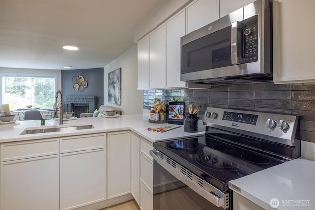 11215 NE 128th St Unit L-203, Kirkland, WA 98034 - kitchen featuring stainless steel appliances, a sink, light countertops, decorative backsplash, and white cabinetry