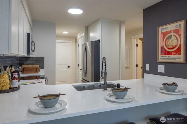 11215 NE 128th St Unit L-203, Kirkland, WA 98034 - kitchen with freestanding refrigerator, white cabinetry, a sink, light countertops, and a peninsula