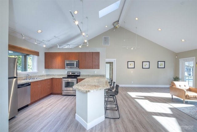 11215 NE 128th St Unit L-203, Kirkland, WA 98034 - kitchen featuring appliances with stainless steel finishes, light wood-style floors, high vaulted ceiling, a skylight, and a peninsula