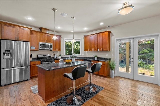 2025 NE 37th Pl, Renton, WA 98056 - kitchen featuring stainless steel appliances, brown cabinetry, light wood-type flooring, a kitchen island, and a breakfast bar area