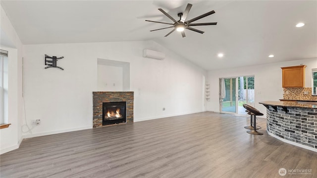 215 19th St, Gold Bar, WA 98251 - unfurnished living room featuring vaulted ceiling, a wall mounted AC, a ceiling fan, a fireplace, and light wood-type flooring