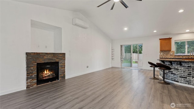 215 19th St, Gold Bar, WA 98251 - living area with a wall mounted air conditioner, vaulted ceiling, a ceiling fan, a stone fireplace, and wood finished floors