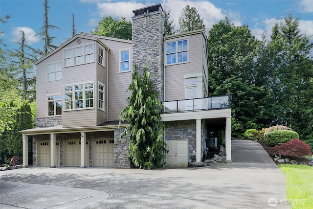 3430 Sevenich Dr, Everett, WA 98201 - view of front facade with stone siding, a garage, concrete driveway, a chimney, and a balcony