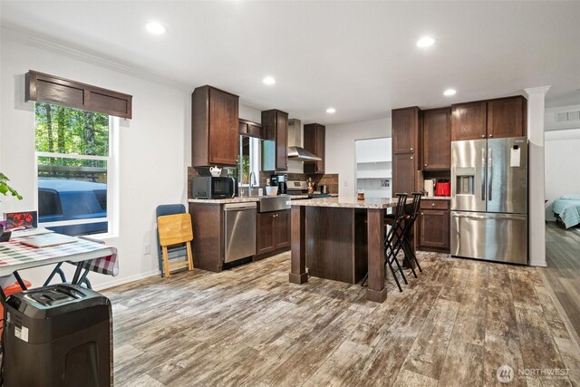 477 SE Old Arcadia Rd, Shelton, WA 98584 - kitchen with appliances with stainless steel finishes, wall chimney exhaust hood, light wood-style flooring, recessed lighting, and a center island