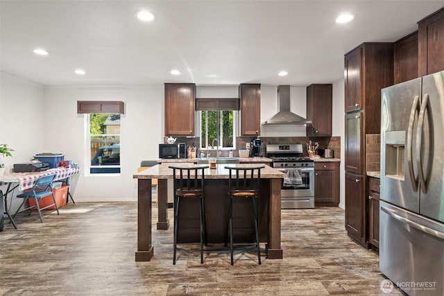 477 SE Old Arcadia Rd, Shelton, WA 98584 - kitchen with stainless steel appliances, wall chimney range hood, recessed lighting, dark wood-style flooring, and a breakfast bar