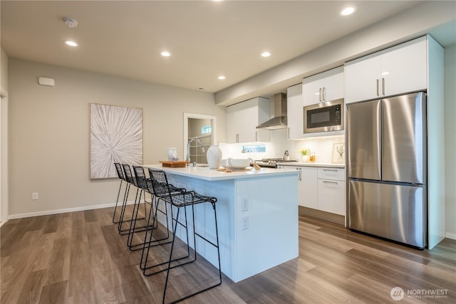 33488 Golden Lakes Ln SE, Black Diamond, WA 98010 - kitchen with stainless steel appliances, wall chimney exhaust hood, white cabinetry, a center island with sink, and dark wood finished floors