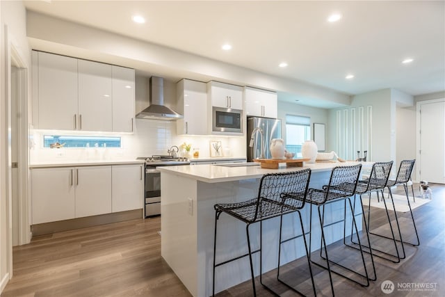 33488 Golden Lakes Ln SE, Black Diamond, WA 98010 - kitchen featuring wall chimney range hood, stainless steel appliances, modern cabinets, a breakfast bar, and recessed lighting