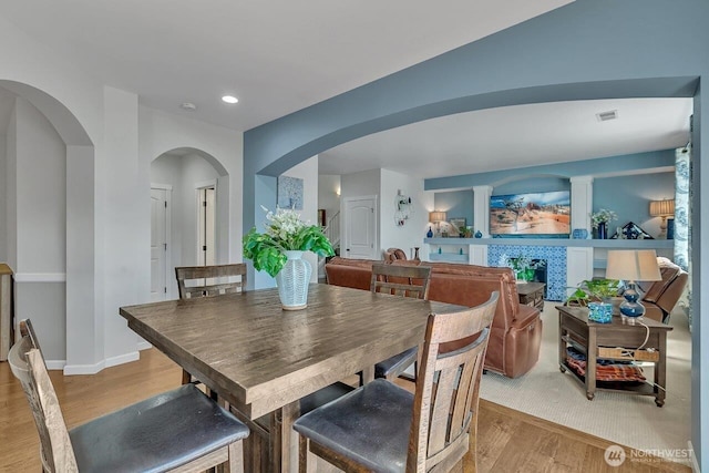 6715 Quincy Ave SE, Auburn, WA 98092 - dining space featuring light wood-style flooring, arched walkways, a tiled fireplace, baseboards, and recessed lighting
