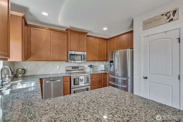 6715 Quincy Ave SE, Auburn, WA 98092 - kitchen featuring stainless steel appliances, a sink, light stone counters, brown cabinetry, and decorative backsplash