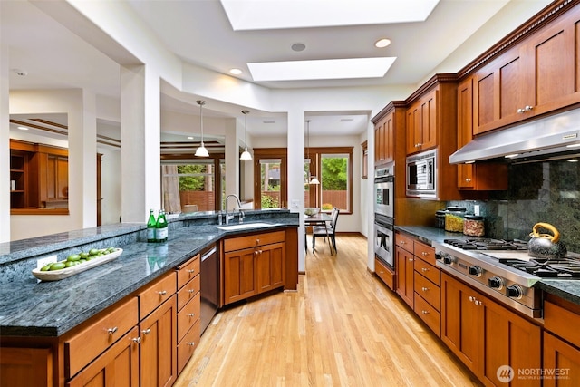 2728 206th Ter NE, Sammamish, WA 98074 - kitchen with stainless steel appliances, light wood-style floors, brown cabinets, under cabinet range hood, and backsplash