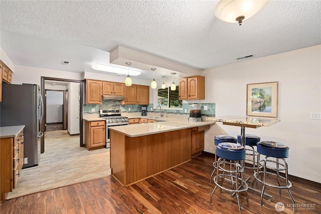3318 18th Ave SE, Olympia, WA 98501 - kitchen with appliances with stainless steel finishes, a peninsula, wood-type flooring, a sink, and under cabinet range hood