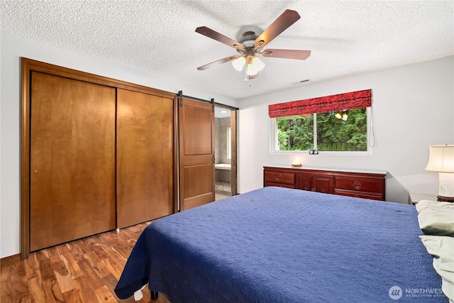 3318 18th Ave SE, Olympia, WA 98501 - bedroom with wood finished floors, a textured ceiling, a barn door, a ceiling fan, and connected bathroom