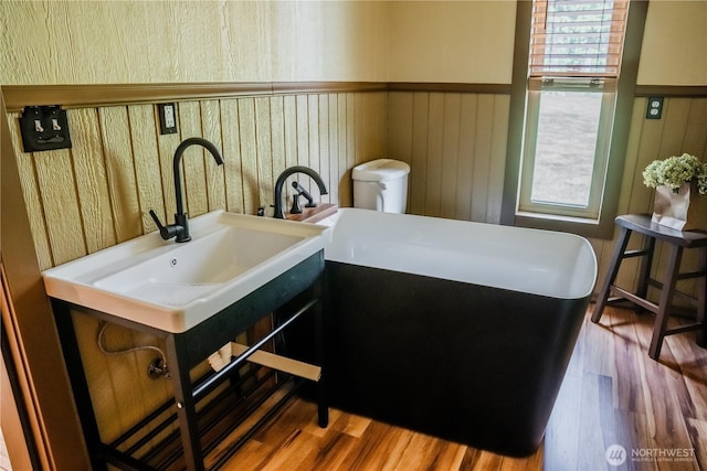 5363 Reese Hill Rd, Sumas, WA 98295 - bathroom with a freestanding tub, wood finished floors, a wainscoted wall, and a sink