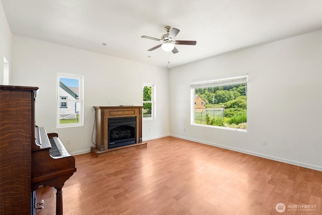 12 Fairgrounds Rd, Skamokawa, WA 98647 - unfurnished living room featuring healthy amount of natural light, light wood-type flooring, ceiling fan, and a fireplace with raised hearth