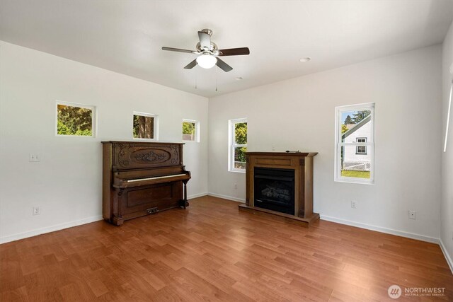 12 Fairgrounds Rd, Skamokawa, WA 98647 - living area with a ceiling fan, wood finished floors, a fireplace with raised hearth, and baseboards