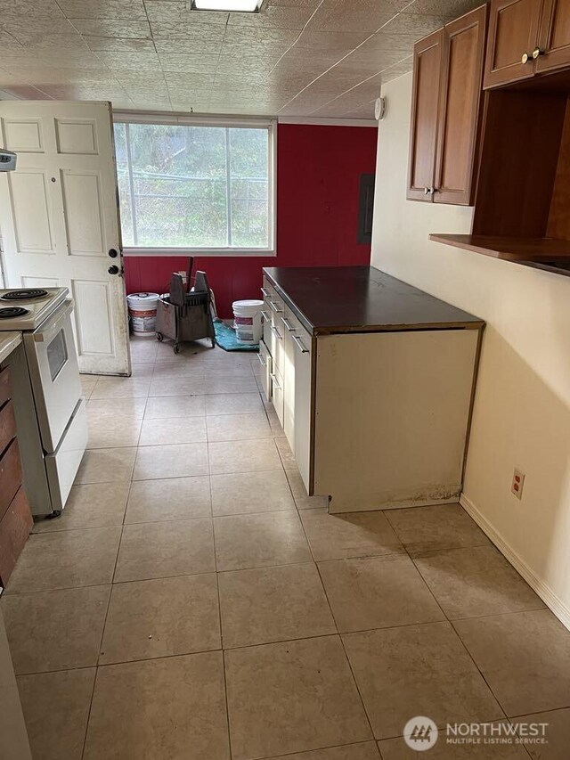27 SW 102nd St, Seattle, WA 98146 - kitchen with white range with electric cooktop, light tile patterned floors, brown cabinets, and dark countertops