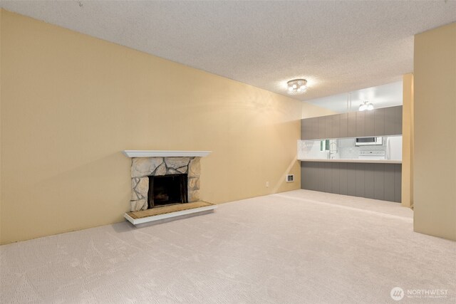 5814 200th St SW Unit D, Lynnwood, WA 98036 - unfurnished living room featuring carpet floors, a fireplace, a textured ceiling, and a sink