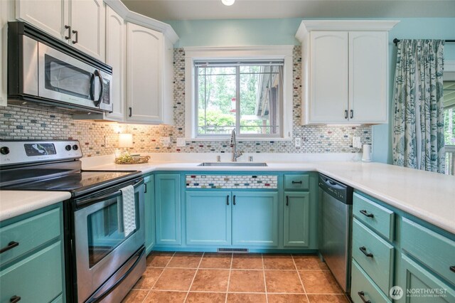 566 Duck Lake Dr SE, Ocean Shores, WA 98569 - kitchen featuring stainless steel appliances, a sink, decorative backsplash, white cabinets, and light countertops