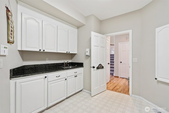 18913 SE 174th Way, Renton, WA 98058 - kitchen featuring light flooring, a sink, white cabinetry, dark stone counters, and baseboards