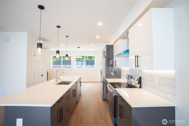 12215 Des Moines Memorial Dr S Unit A, Burien, WA 98168 - kitchen featuring stainless steel appliances, light wood-style flooring, a center island with sink, white cabinets, and ventilation hood