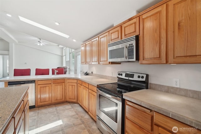 302 Oak St SW, Orting, WA 98360 - kitchen featuring stainless steel appliances, a sink, light countertops, a ceiling fan, and a peninsula
