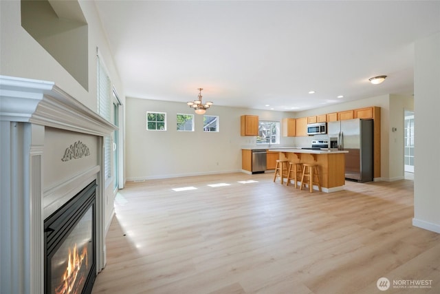 3147 6th Ave NW, Olympia, WA 98502 - living area featuring a glass covered fireplace, light wood-type flooring, baseboards, a chandelier, and plenty of natural light