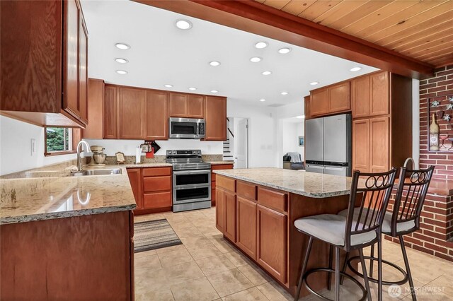 8402 57th Ave E, Puyallup, WA 98371 - kitchen featuring stainless steel appliances, light tile patterned flooring, a sink, a center island, and light stone countertops