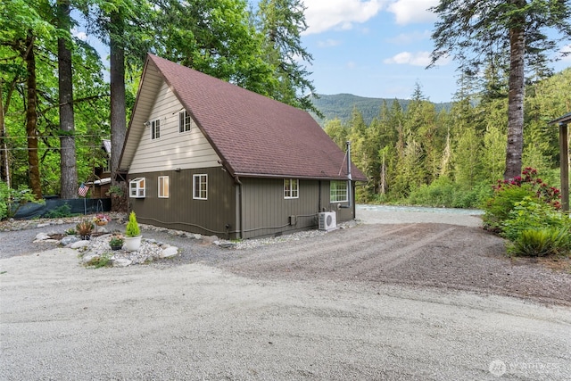 25921 Clear Creek Rd, Darrington, WA 98241 - view of side of home with roof with shingles, driveway, a cooling unit, a mountain view, and a view of trees