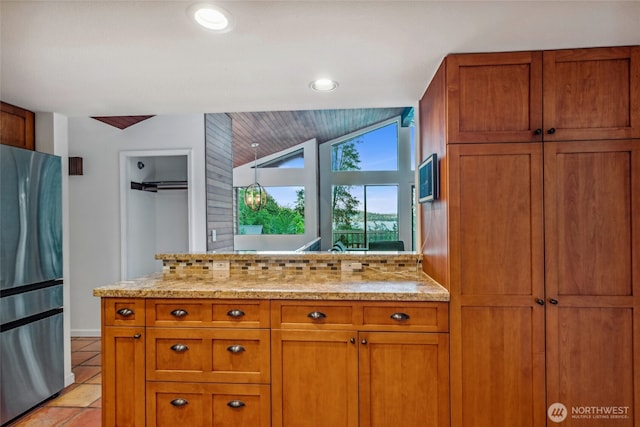 4119 NE 142nd St, Seattle, WA 98125 - kitchen featuring freestanding refrigerator, brown cabinetry, light stone countertops, vaulted ceiling, and tasteful backsplash
