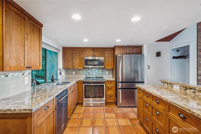 4119 NE 142nd St, Seattle, WA 98125 - kitchen with stainless steel appliances, brown cabinets, tasteful backsplash, light stone counters, and recessed lighting