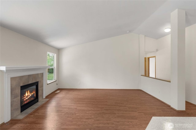 502 NW Alexander Ct, Orting, WA 98360 - unfurnished living room featuring lofted ceiling, wood finished floors, and a tile fireplace