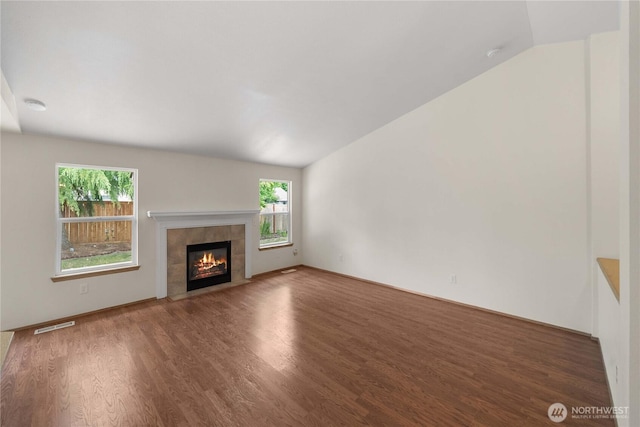 502 NW Alexander Ct, Orting, WA 98360 - unfurnished living room with vaulted ceiling, wood finished floors, a tile fireplace, and plenty of natural light
