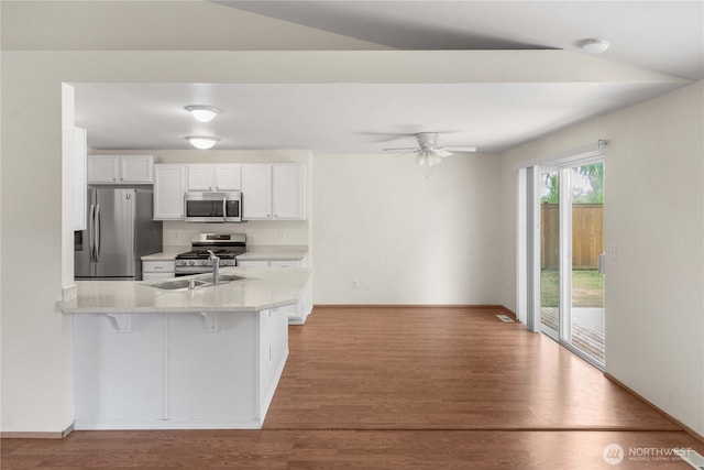 502 NW Alexander Ct, Orting, WA 98360 - kitchen featuring appliances with stainless steel finishes, light countertops, a peninsula, white cabinets, and wood finished floors