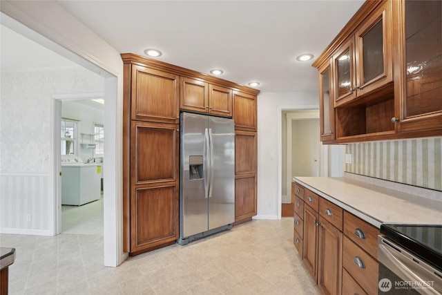 636 20th Ave, Longview, WA 98632 - kitchen featuring stainless steel appliances, washing machine and clothes dryer, light countertops, brown cabinetry, and glass insert cabinets