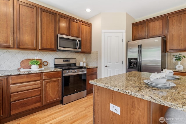 27677 256th Pl SE, Maple Valley, WA 98038 - kitchen with appliances with stainless steel finishes, light wood-style flooring, light stone counters, tasteful backsplash, and recessed lighting