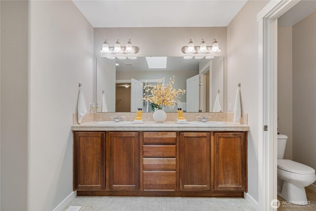27677 256th Pl SE, Maple Valley, WA 98038 - full bath featuring double vanity, toilet, baseboards, and a skylight