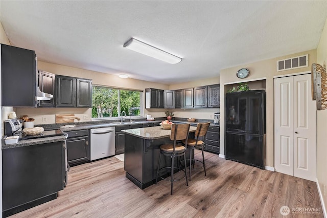5110 Regan Rd, Cashmere, WA 98815 - kitchen with freestanding refrigerator, stainless steel dishwasher, a sink, a breakfast bar area, and light wood-style flooring