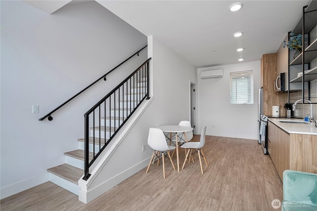 1300 E Remington Ct Unit B, Seattle, WA 98122 - kitchen with a wall mounted air conditioner, light wood finished floors, stainless steel appliances, light countertops, and recessed lighting