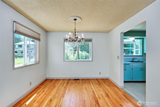 434 T St, Port Townsend, WA 98368 - unfurnished dining area featuring a textured ceiling, a sink, light wood finished floors, a chandelier, and baseboards