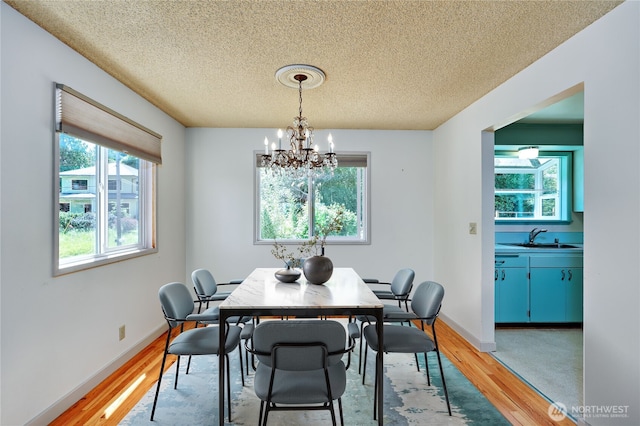 434 T St, Port Townsend, WA 98368 - dining room featuring light wood finished floors, a textured ceiling, a chandelier, and baseboards