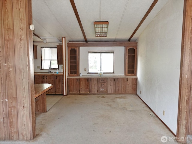 676 Copalis Ave NE, Ocean Shores, WA 98569 - kitchen featuring light colored carpet, brown cabinetry, a sink, and wooden walls