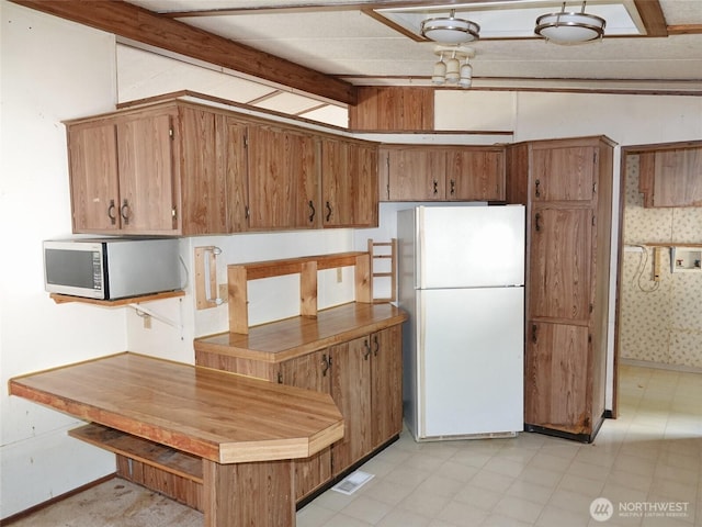 676 Copalis Ave NE, Ocean Shores, WA 98569 - kitchen with freestanding refrigerator, stainless steel microwave, brown cabinets, and light flooring