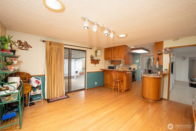 10930 38th Dr SE, Everett, WA 98208 - kitchen featuring light wood finished floors, brown cabinets, a peninsula, a textured ceiling, and light countertops