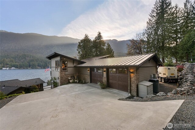 76 Thompson Point Rd, Port Angeles, WA 98363 - view of front facade featuring a standing seam roof, driveway, a garage, stone siding, and metal roof