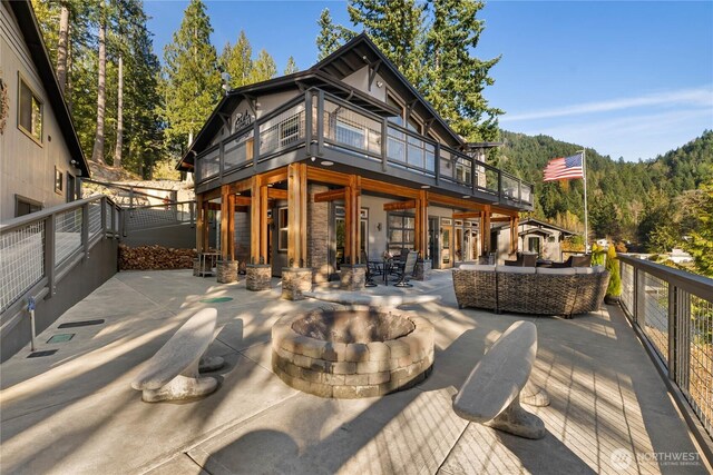 76 Thompson Point Rd, Port Angeles, WA 98363 - rear view of house featuring an outdoor living space with a fire pit, a patio, and a wooded view