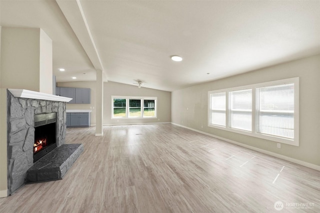 20119 120th Ave E, Graham, WA 98338 - unfurnished living room featuring a stone fireplace, vaulted ceiling, baseboards, and light wood-style floors