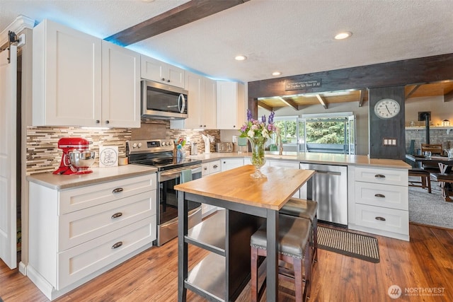 1598 Tedford St SE, East Wenatchee, WA 98802 - kitchen with stainless steel appliances, a peninsula, beam ceiling, backsplash, and a textured ceiling